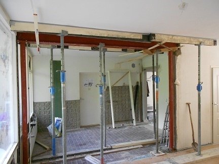 Stalen draagbalk in een doorgebroken muur, met stempels